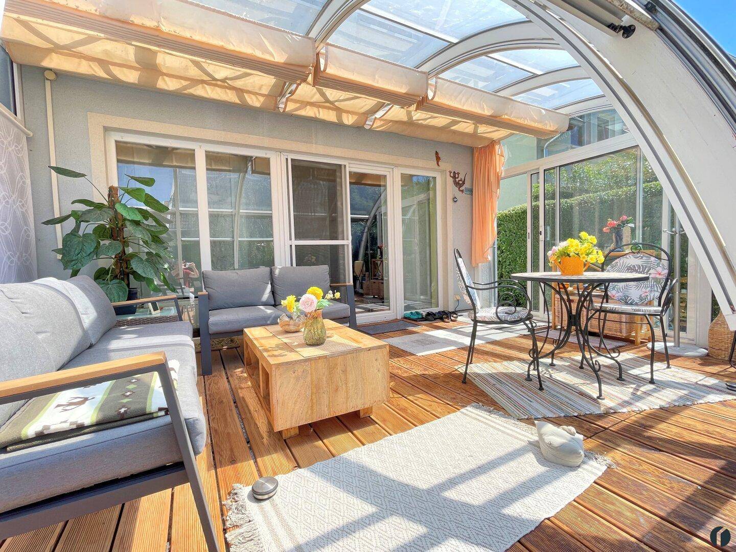 Überdachte Terrasse mit Glasdach, Holzdeck und gemütlichen Gartenmöbeln für entspannte Stunden.