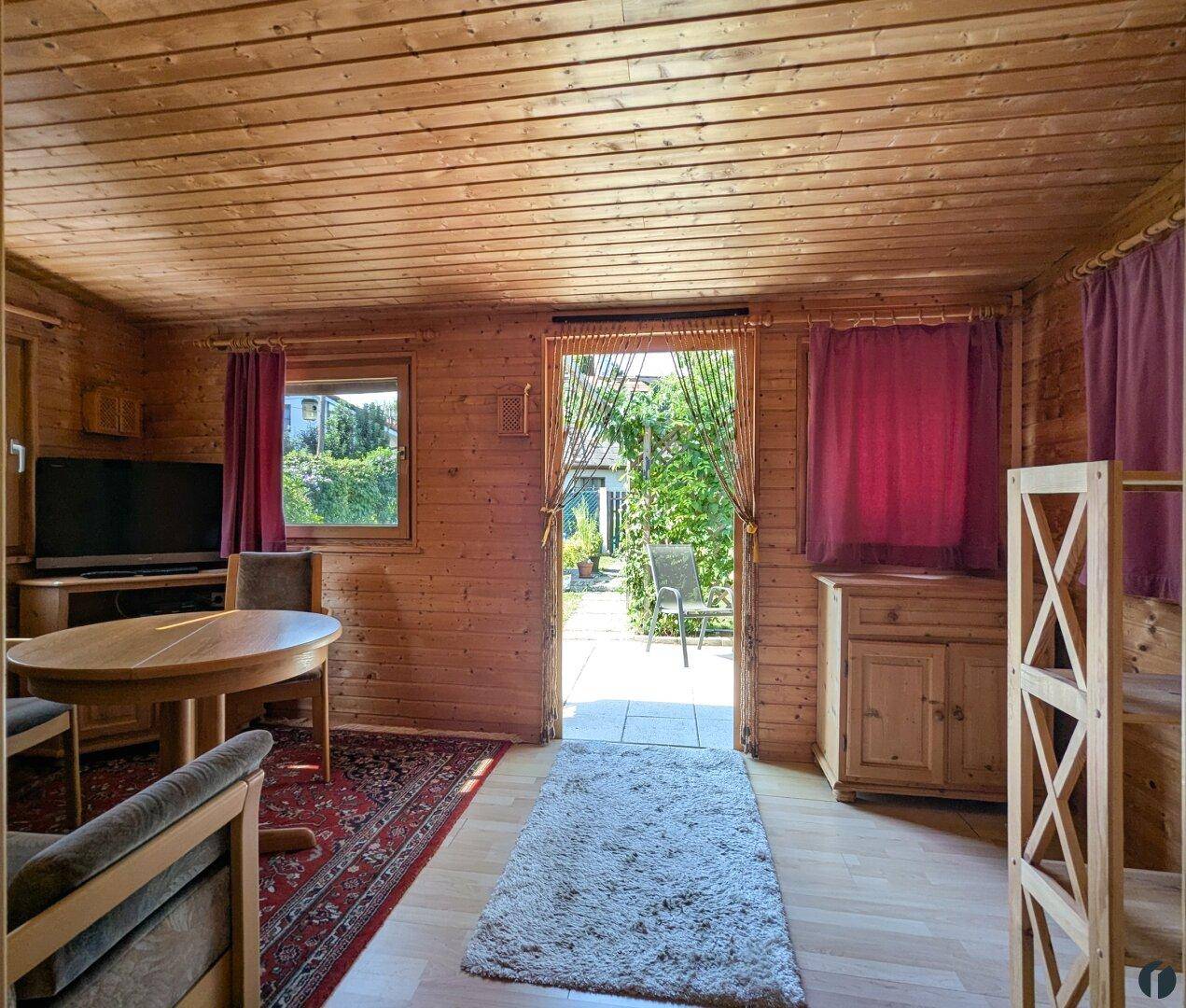 Rustikales Wohnzimmer im Holzhaus mit Holzwänden, Holzboden und direktem Zugang zur Terrasse.