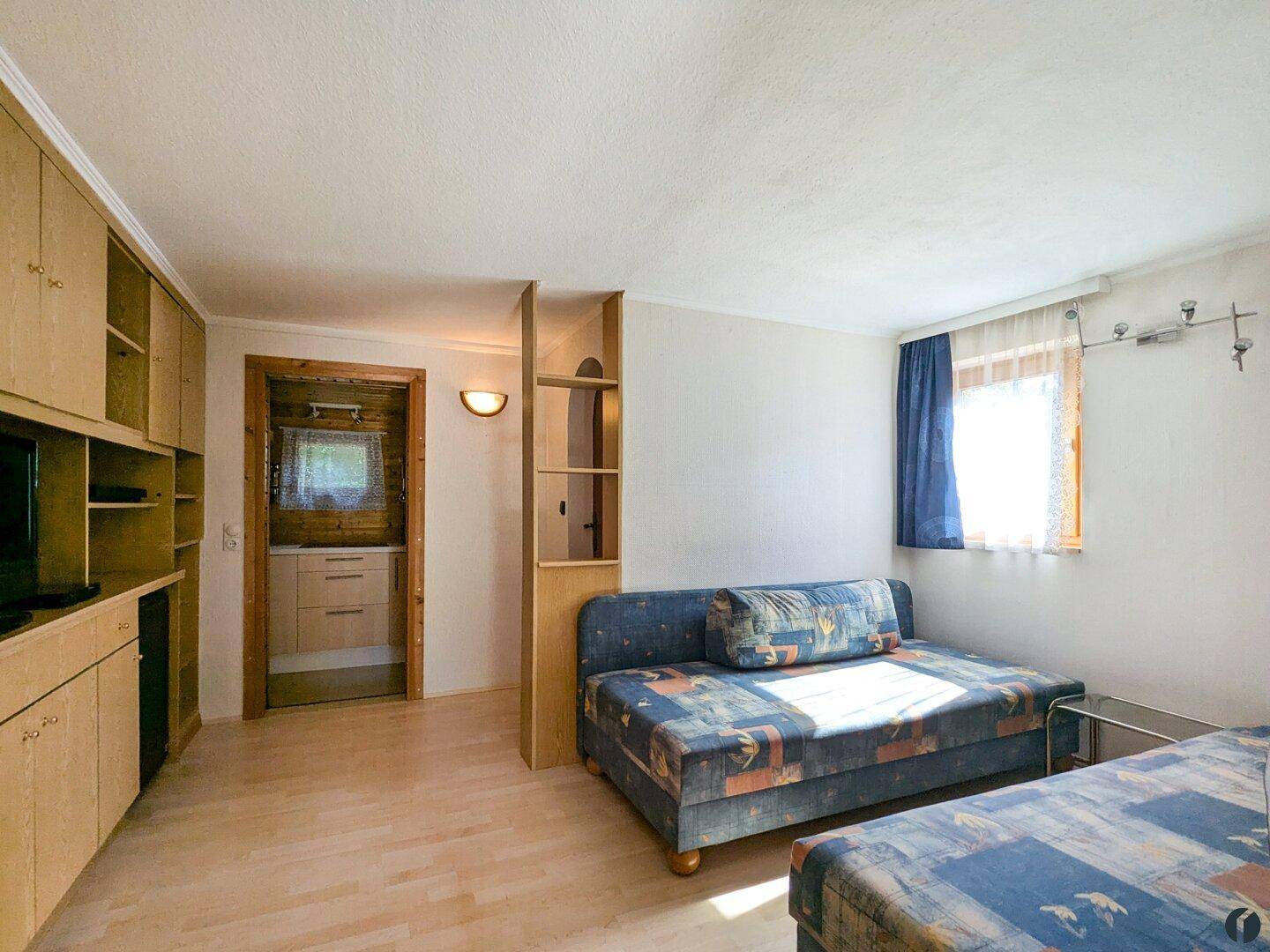 Heller Raum mit Einbauschränken, Schlafsofa und Zugang zu einem angrenzenden Badezimmer.
