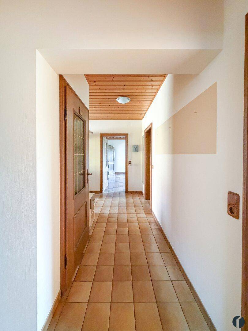 Heller Flur mit Fliesenboden, Holzdecke und Holztüren.