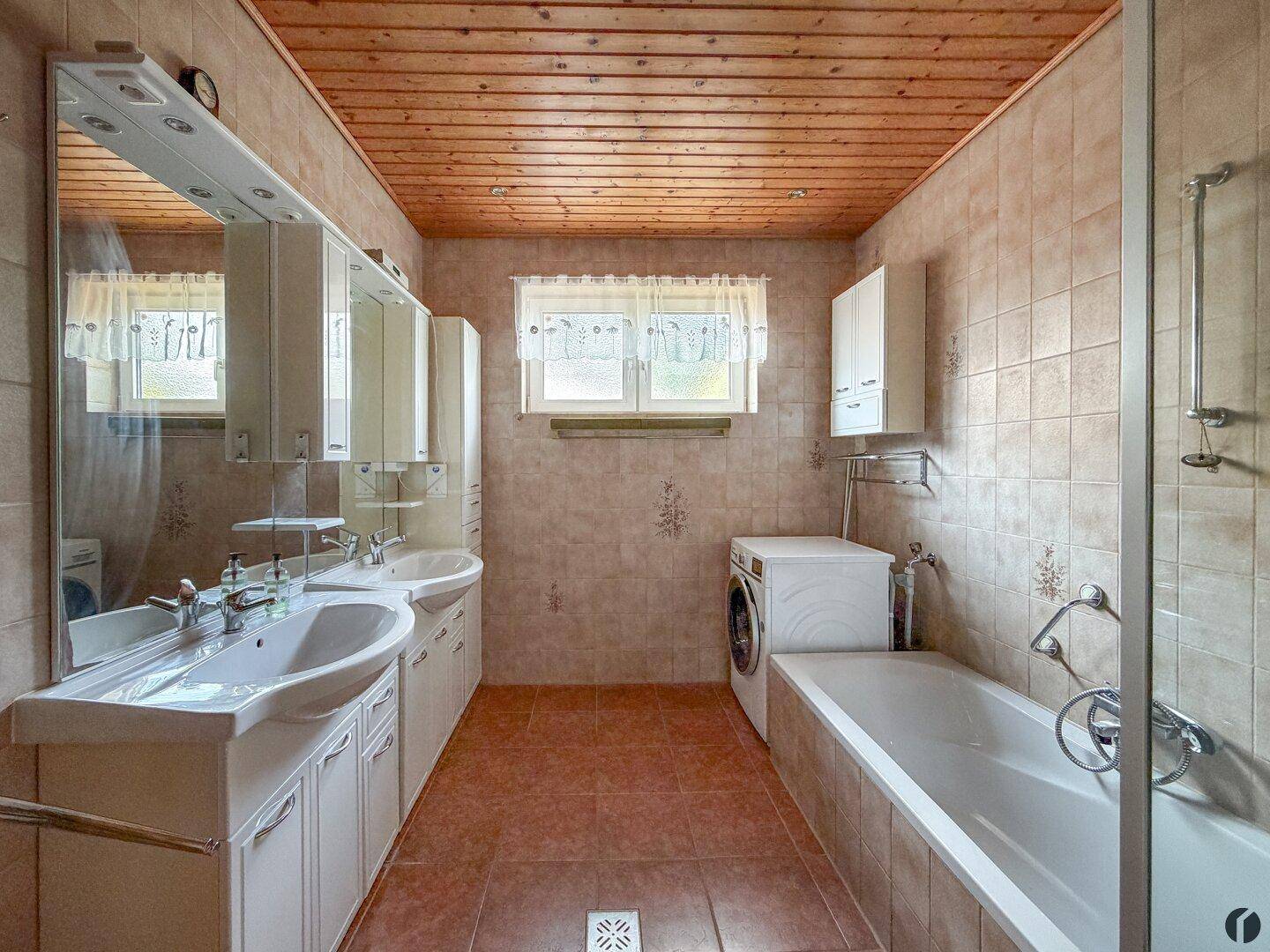 Geräumiges Badezimmer mit Doppelwaschbecken, Badewanne und Fenster.