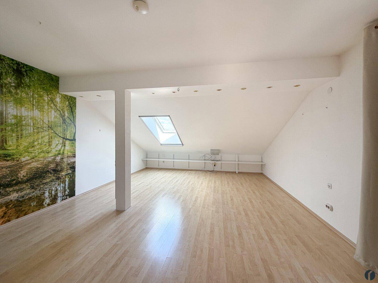 Großzügiger Dachbodenraum mit Laminatboden, Dachfenster und Schrägen.