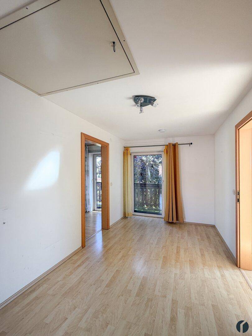 Helles Zimmer mit Laminatboden, Zugang zum Balkon und Dachbodenluke.