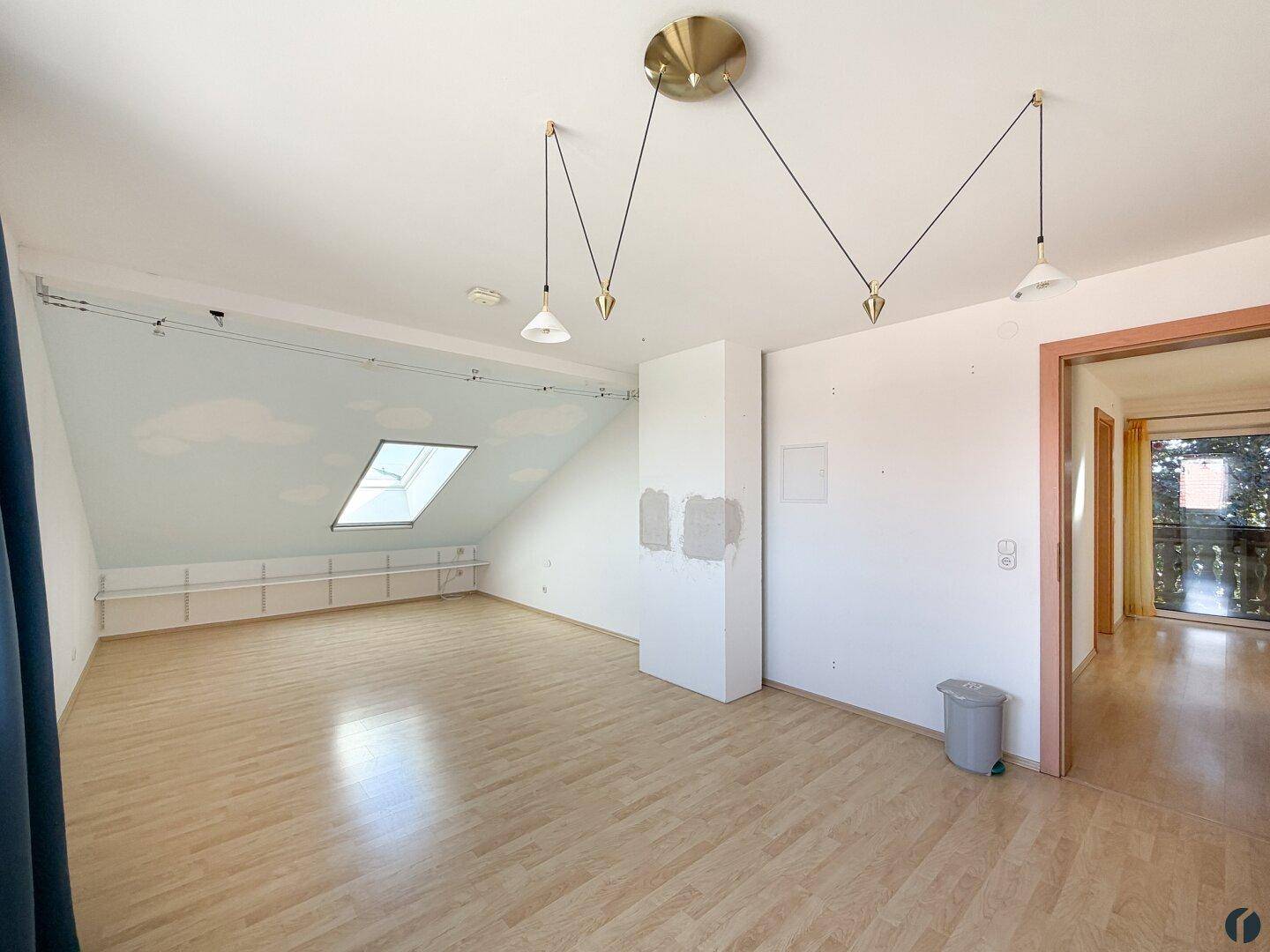 Offener Dachbodenraum mit Laminatboden, Dachschrägen und moderner Beleuchtung.