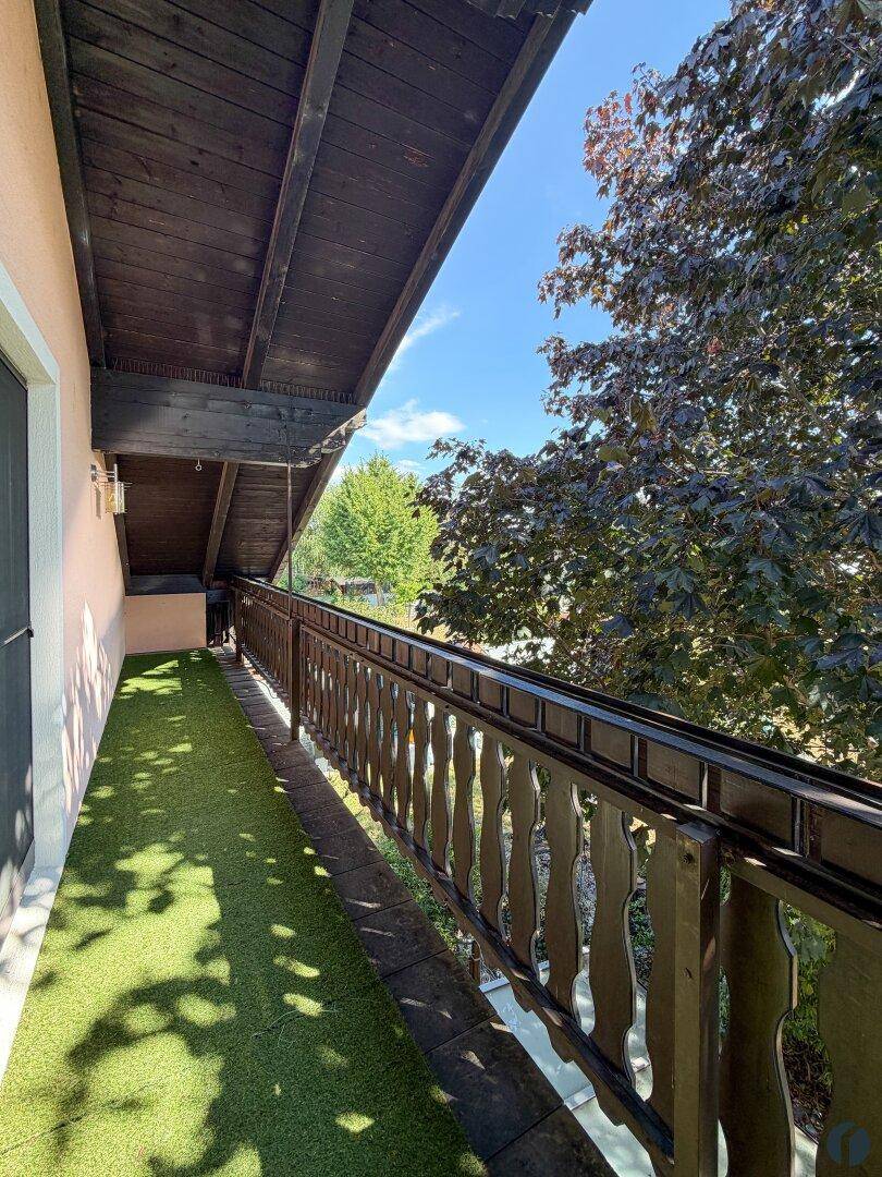 Balkon mit Kunstrasen, Holzgeländer und Blick ins Grüne.