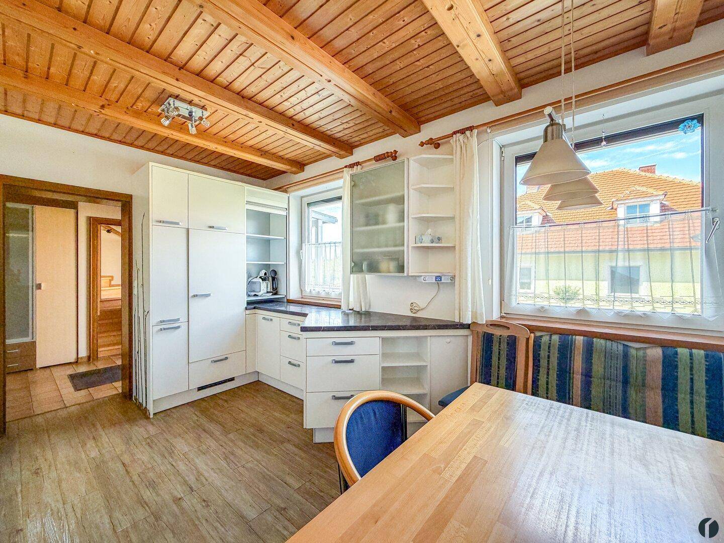 Helle Wohnküche mit Essbereich, viel Stauraum und Fenster mit Ausblick.