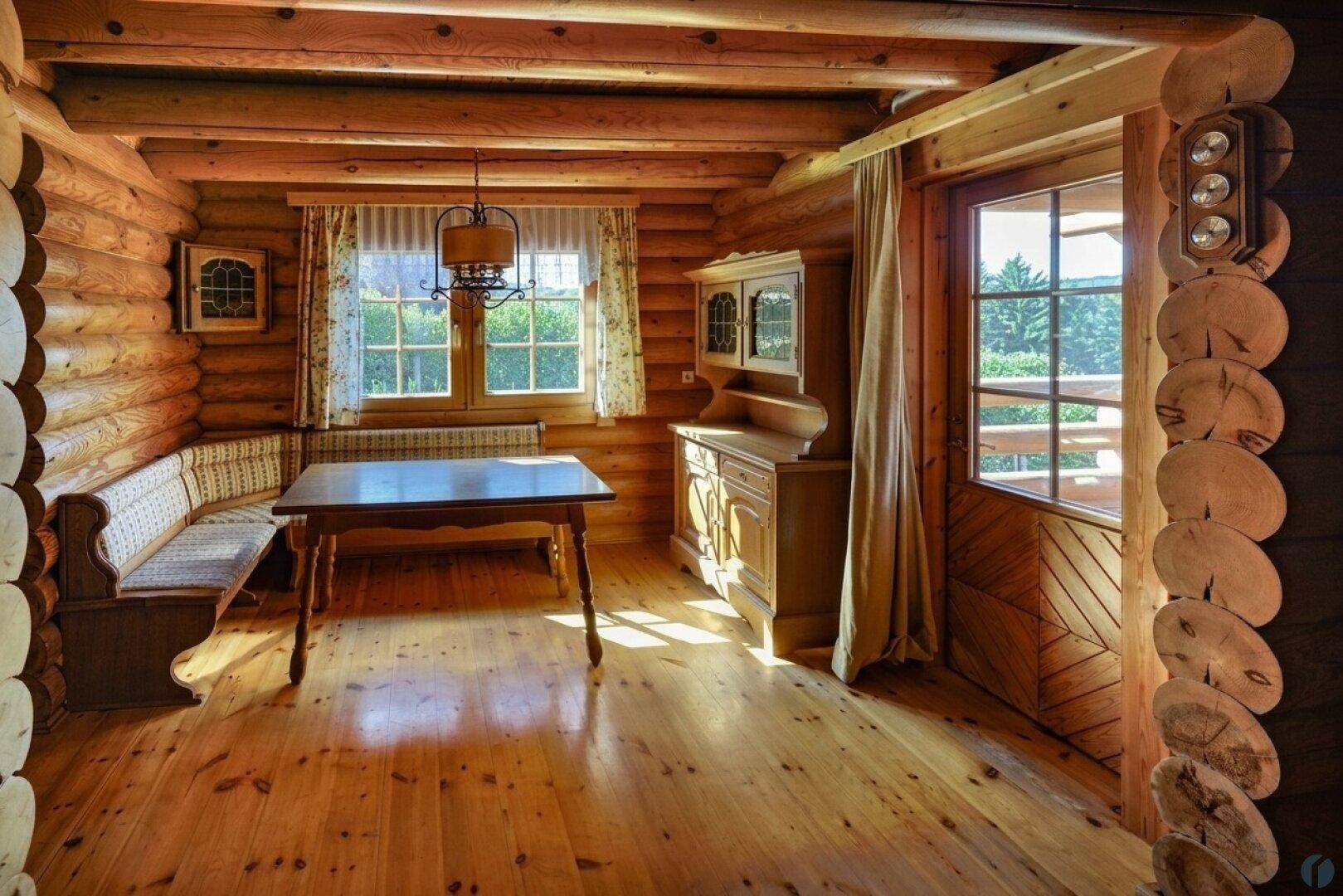 Gemütlicher Essbereich im Blockhaus mit Holzbalken, Holztisch und traditioneller Eckbank.