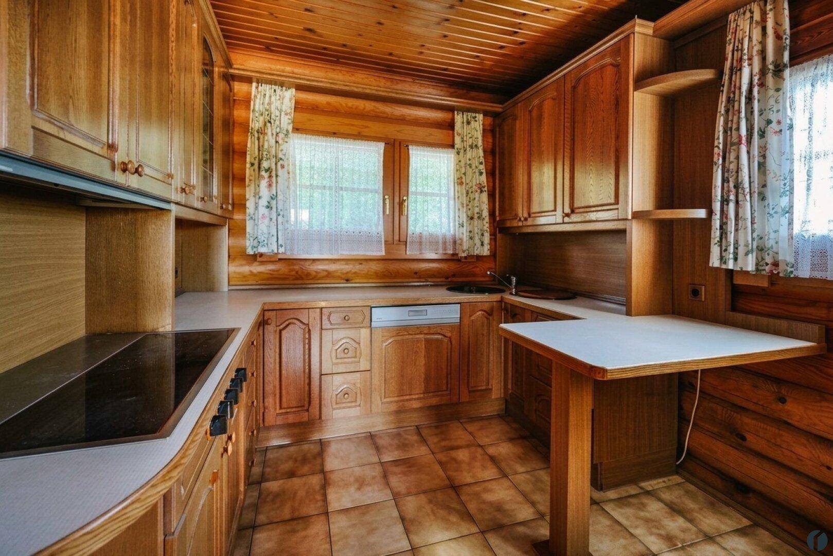 Rustikale Küche im Blockhaus mit Holzschränken, Fliesenboden und integrierten Geräten.