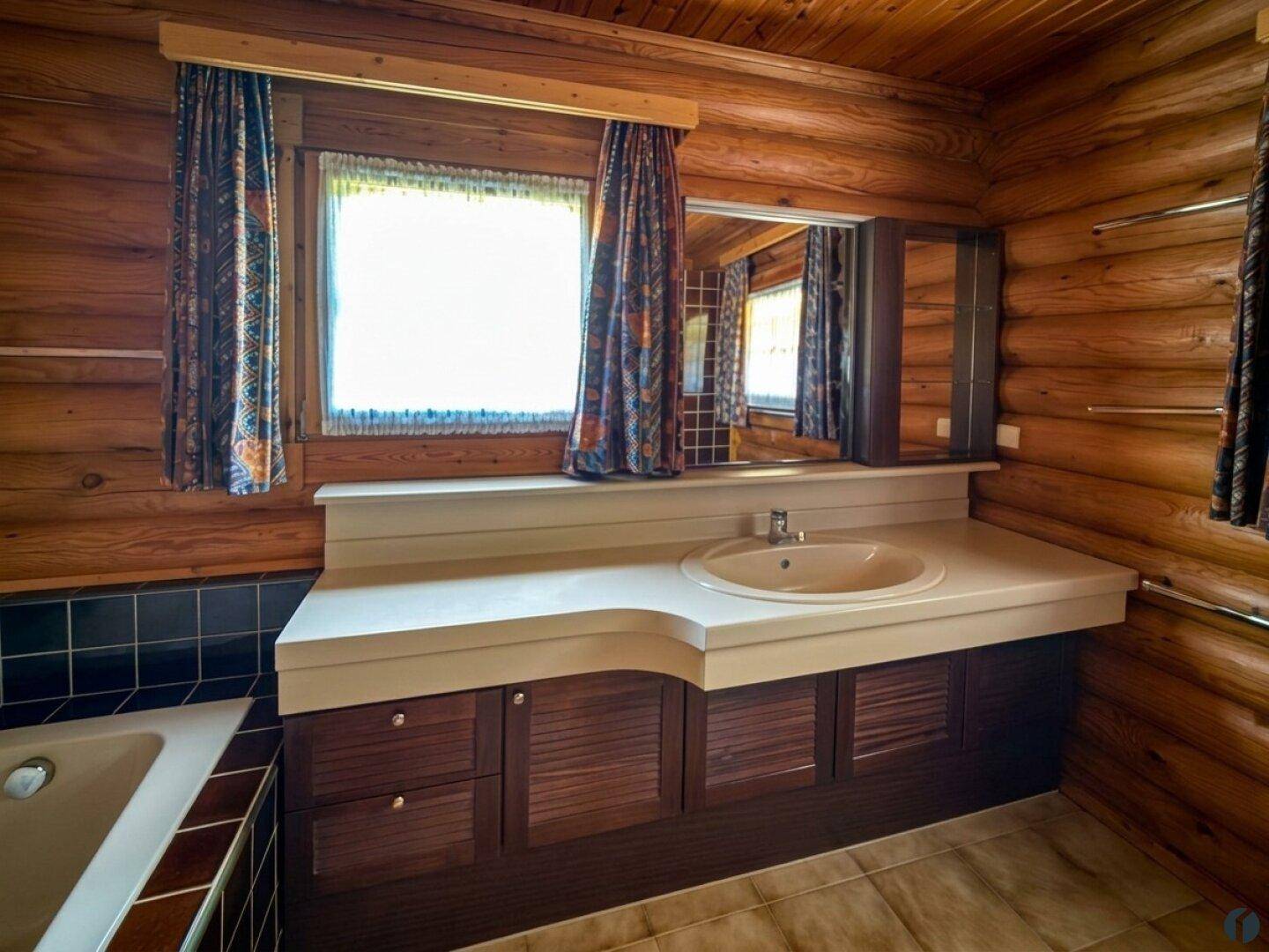 Badezimmer im Blockhausstil mit Holzverkleidung, Einzelwaschbecken und Spiegelschrank.