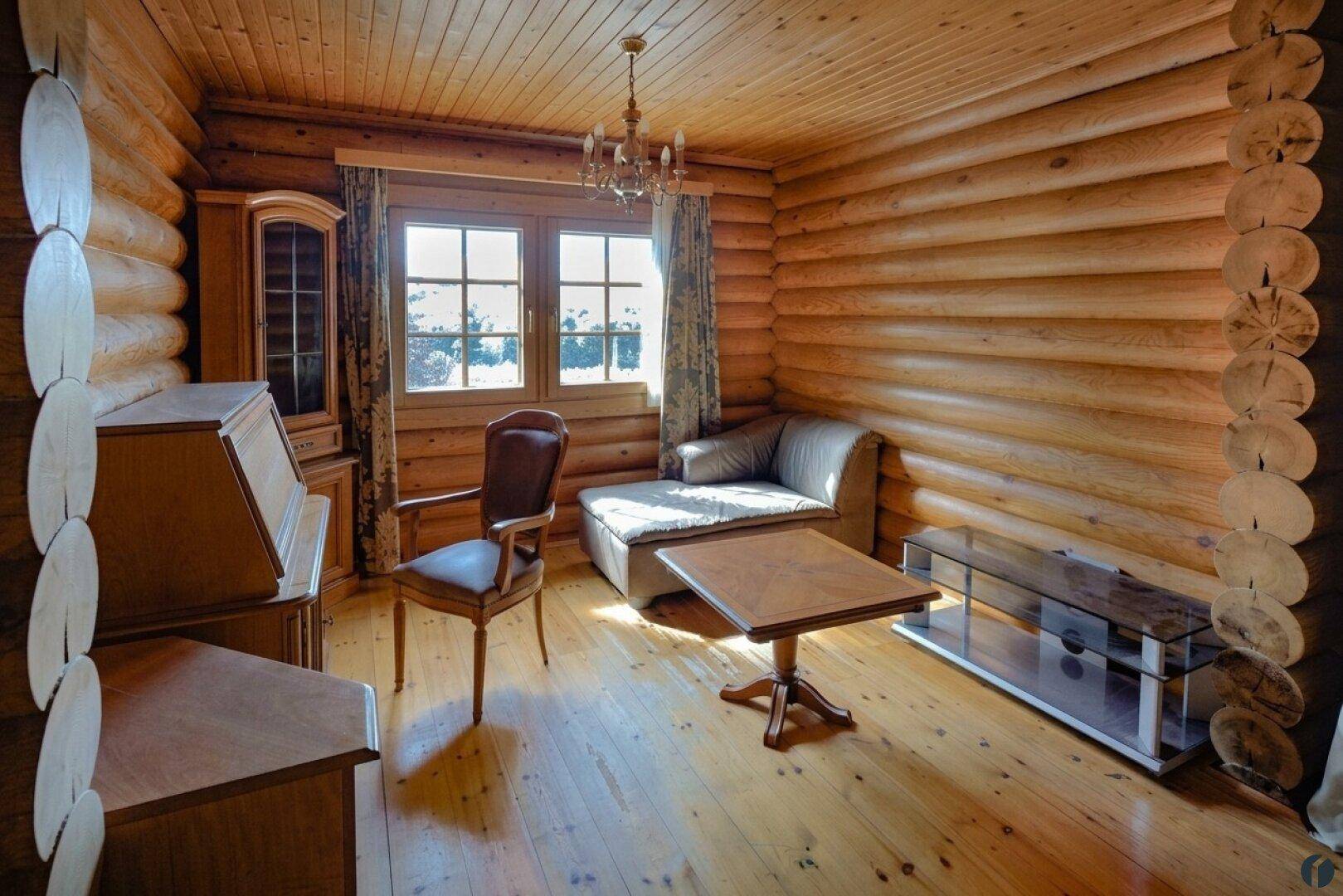 Gemütlicher Raum im Blockhaus mit Holzwänden, Parkettboden und klassischer Einrichtung.