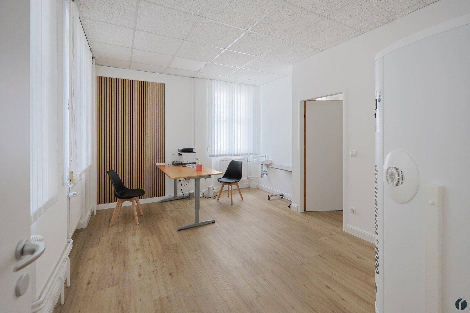 Modernes Büro oder Behandlungszimmer mit Holzwandverkleidung, Schreibtisch und natürlichem Lichteinfall.