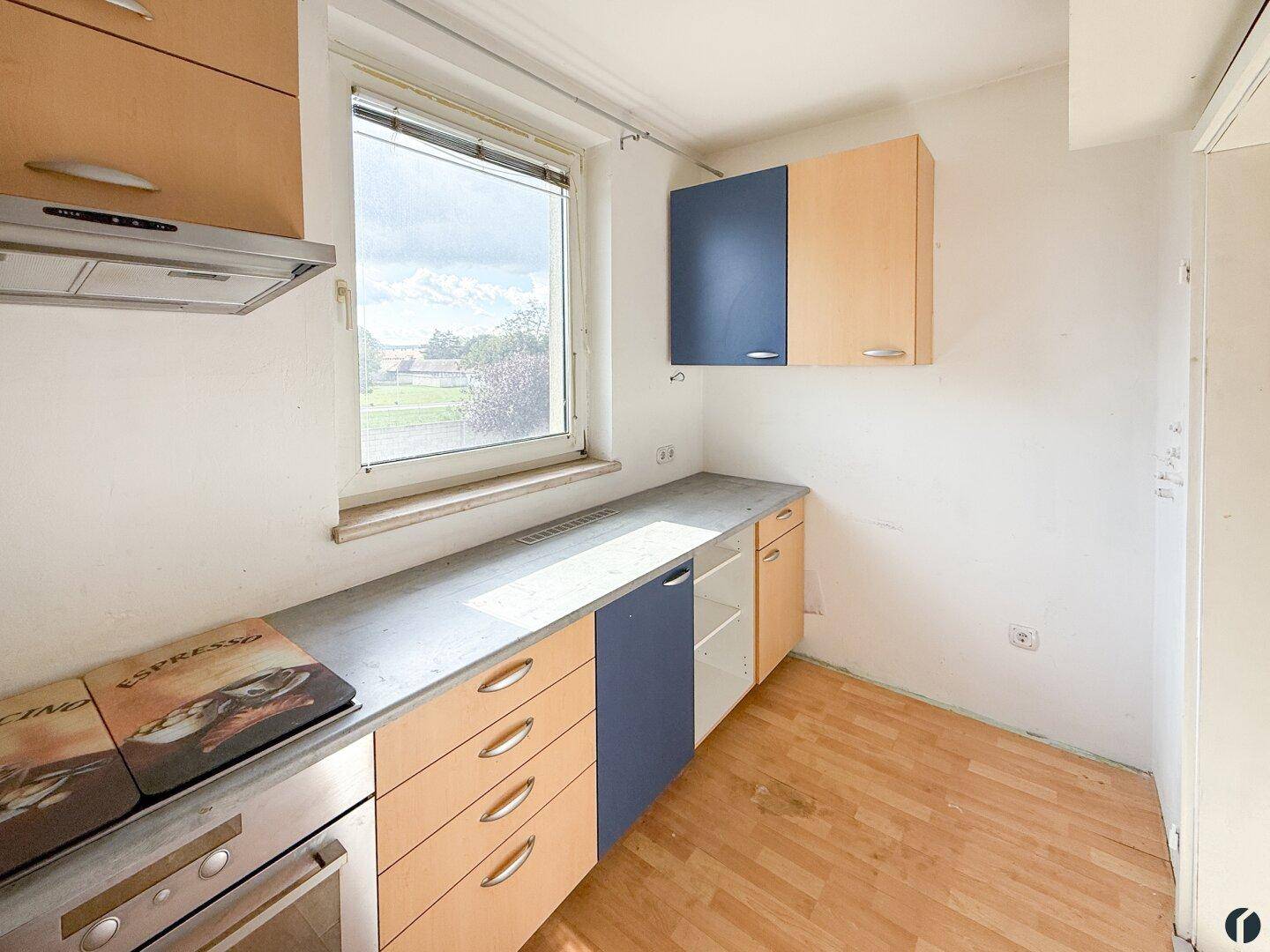 Küche mit Holzschränken, Arbeitsplatte, Spüle und einem Fenster, bereit zur Nutzung.