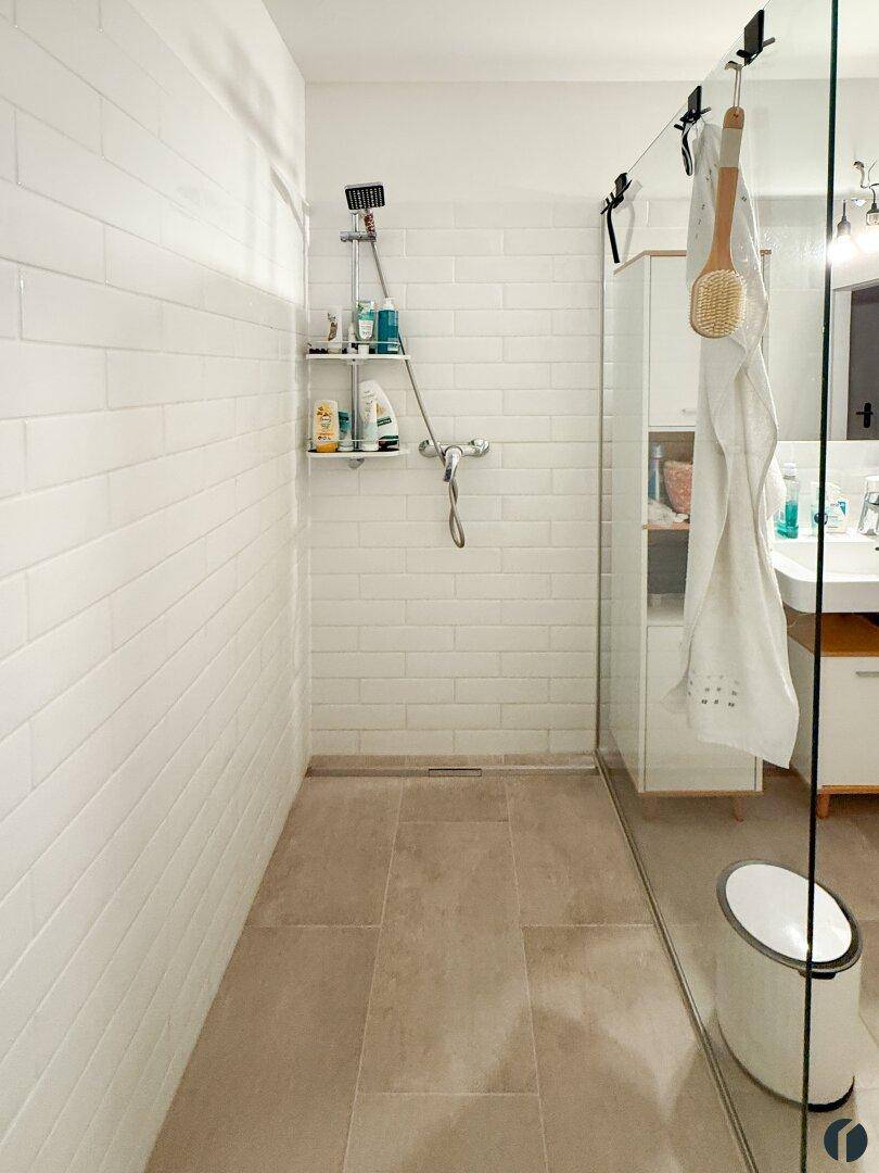 Geräumige, begehbare Dusche mit weißen Metrofliesen und bodengleichem Zugang im Badezimmer.