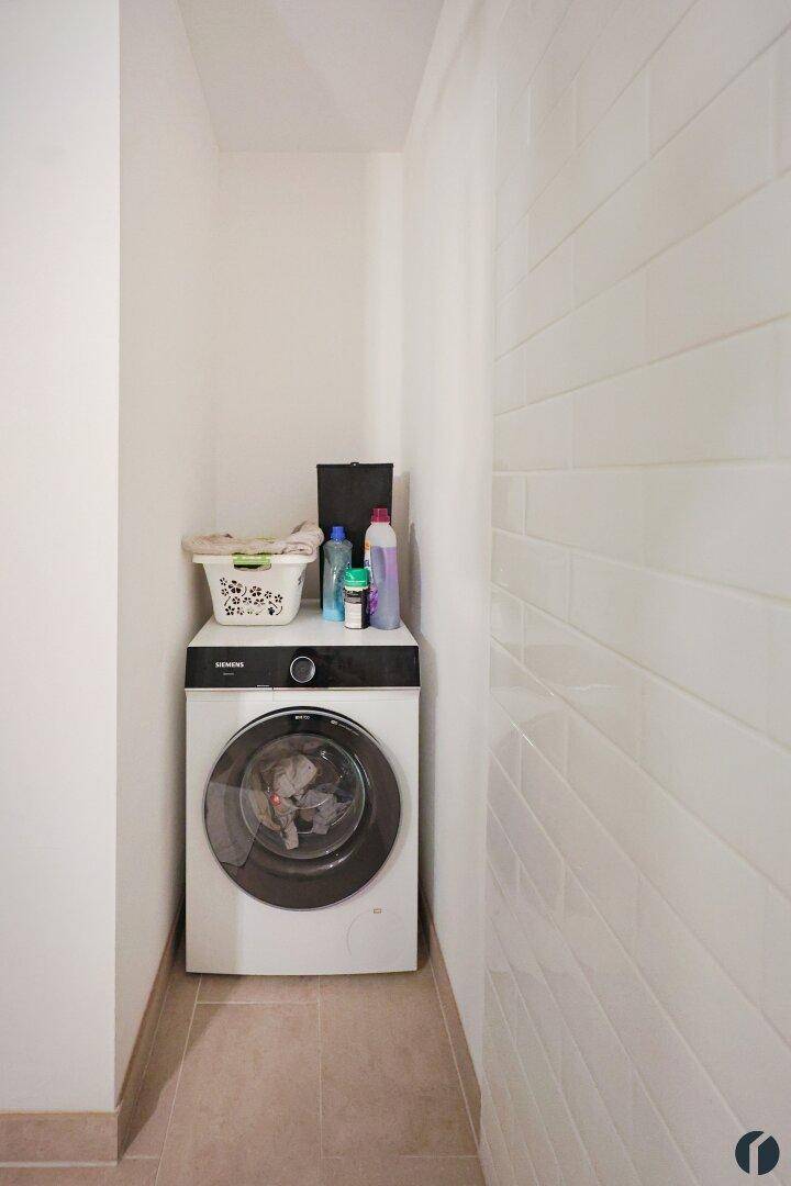Kleiner Hauswirtschaftsraum mit Waschmaschine und weißen Wandfliesen, praktisch und funktional.