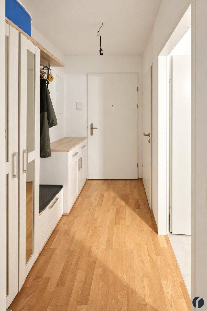 Heller Eingangsbereich mit Garderobe, Spiegel und Holzfußboden, einladend und funktional.