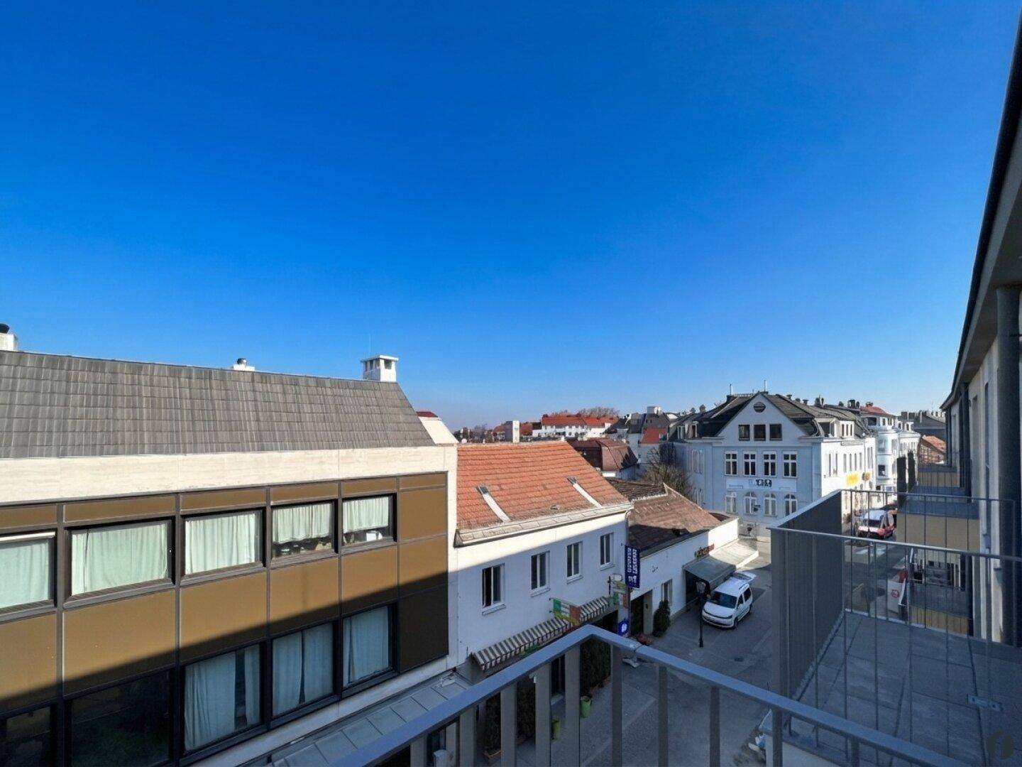 Blick von oben auf eine belebte Straße mit Gebäuden und Fahrzeugen, städtisches Panorama.