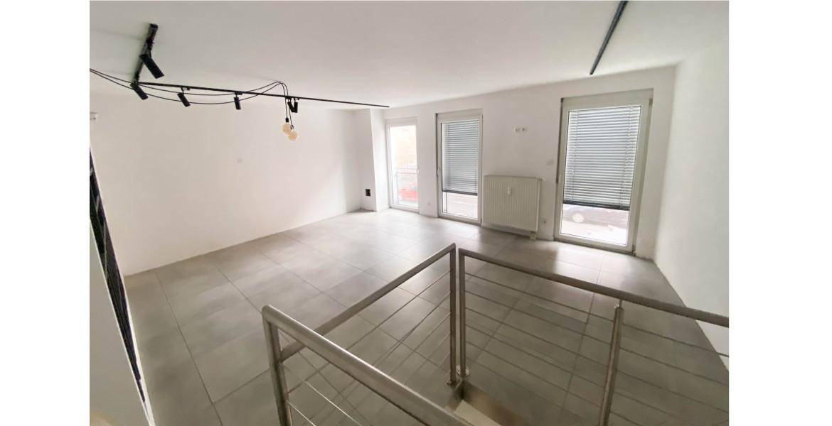 Großer, offener Raum mit Fliesenboden, großen Fenstern und Blick auf die Straße.