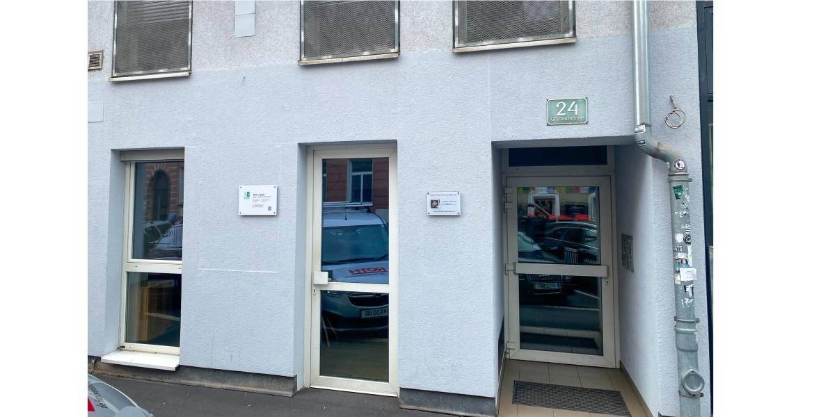 Moderne Gebäudefassade mit großen Fenstern und Eingangsbereichen auf Straßenniveau.