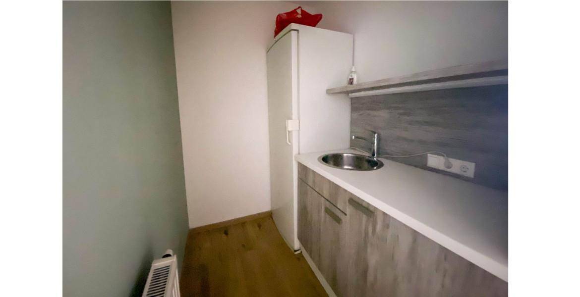 Kleine Teeküche mit Spüle, Kühlschrank und Holzoptik-Schränken.