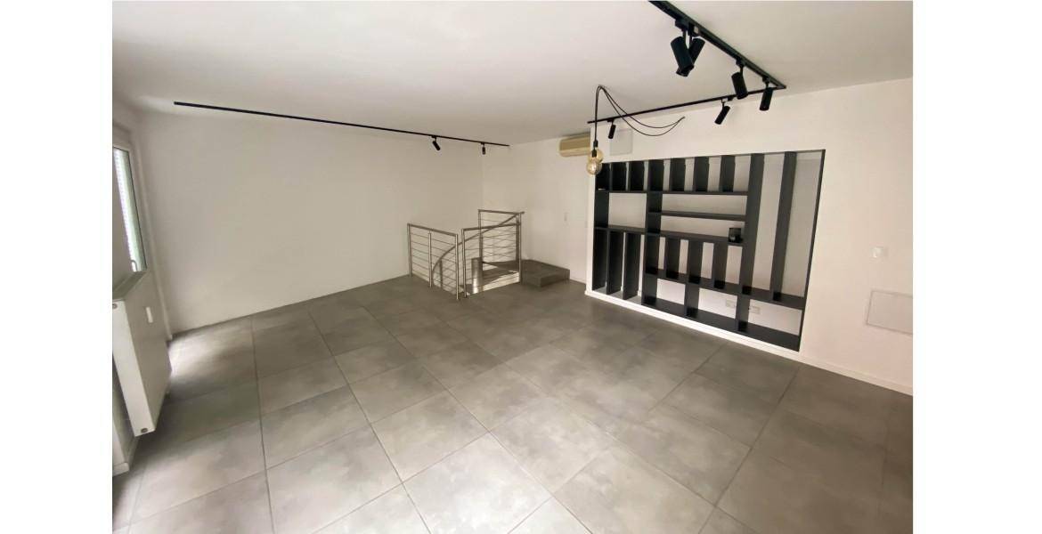 Geräumiger Wohnbereich mit Fliesenboden, integriertem Regal und moderner Beleuchtung.