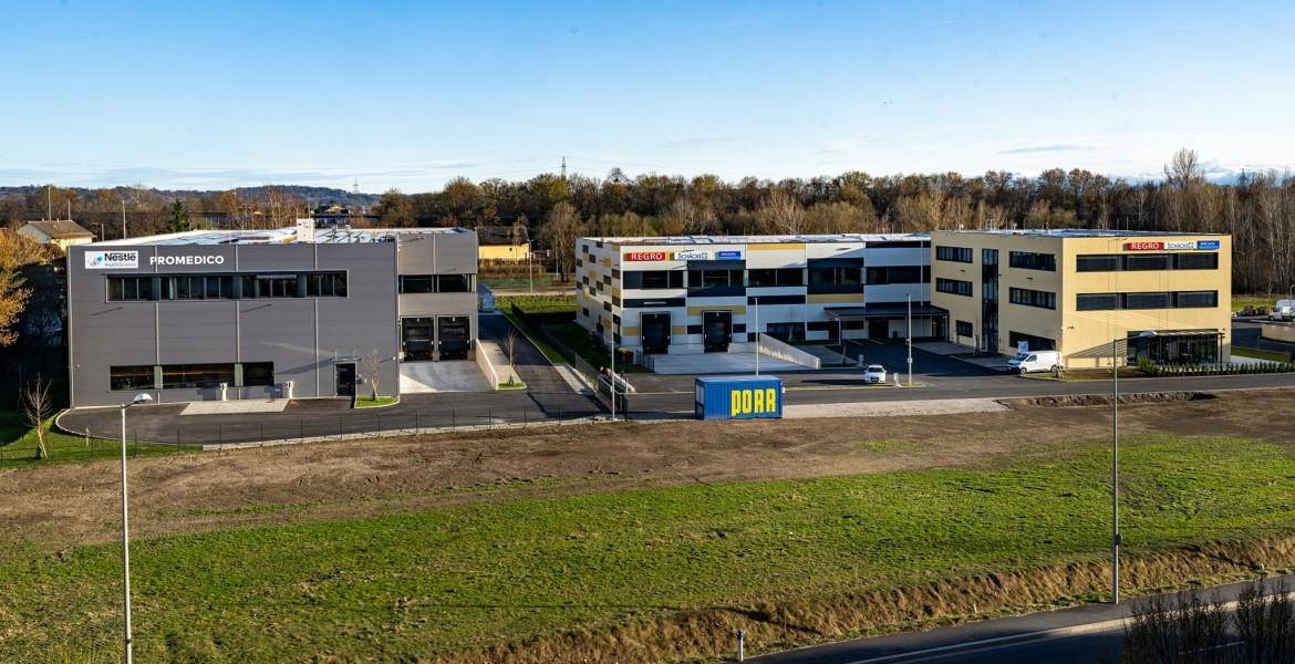 Ansicht von modernen Geschäftsgebäuden in einem Gewerbepark mit gepflegten Grünflächen und einer Zufahrtsstraße.