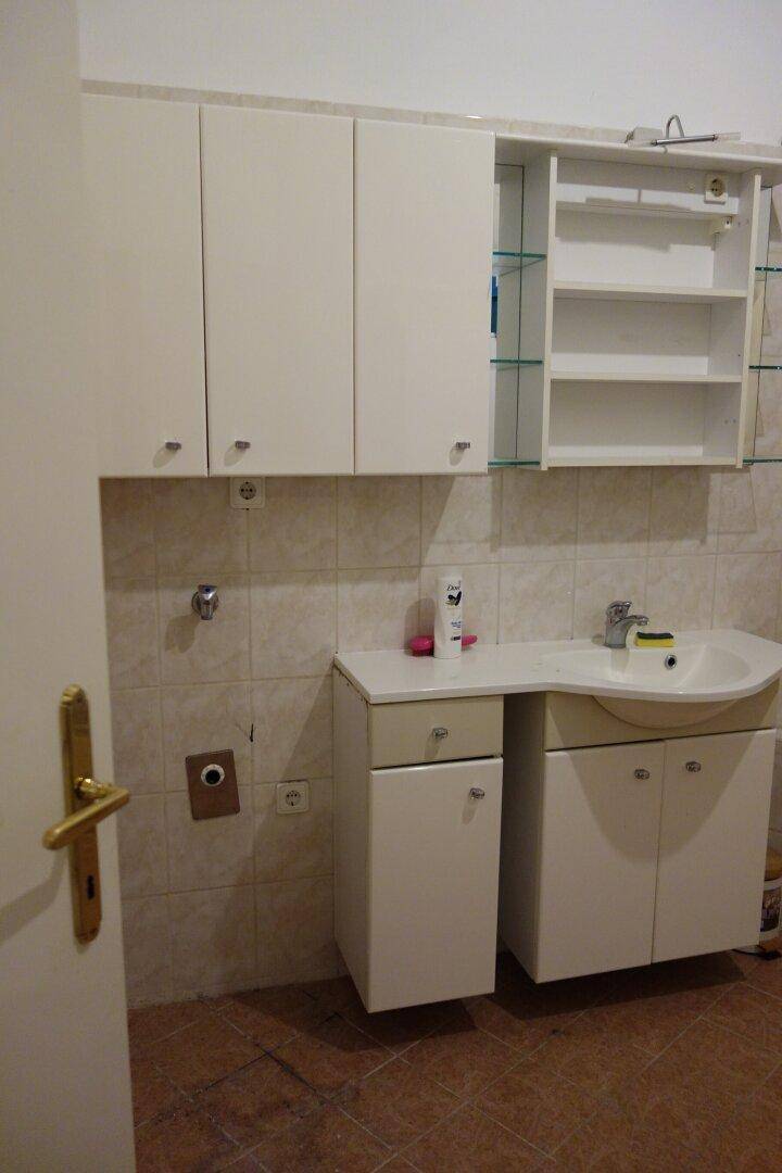 Badezimmer mit Waschbecken, Spiegelschrank und praktischen Hängeschränken, hell gefliest.