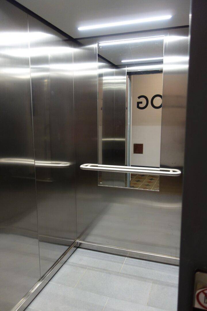 Moderner Aufzug mit Edelstahloberflächen und integriertem Handlauf, bietet bequemen Zugang zu den Etagen.