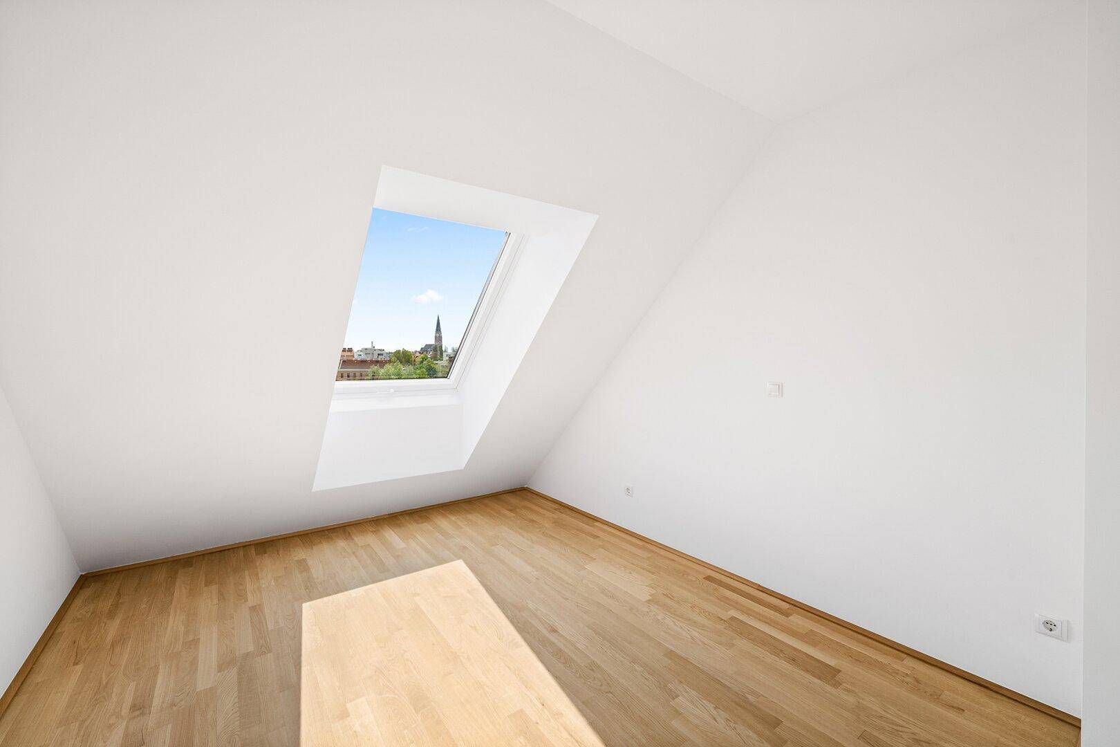 Gemütliches Zimmer im Dachgeschoss mit Holzboden und einem Dachfenster, das einen Stadtblick bietet.