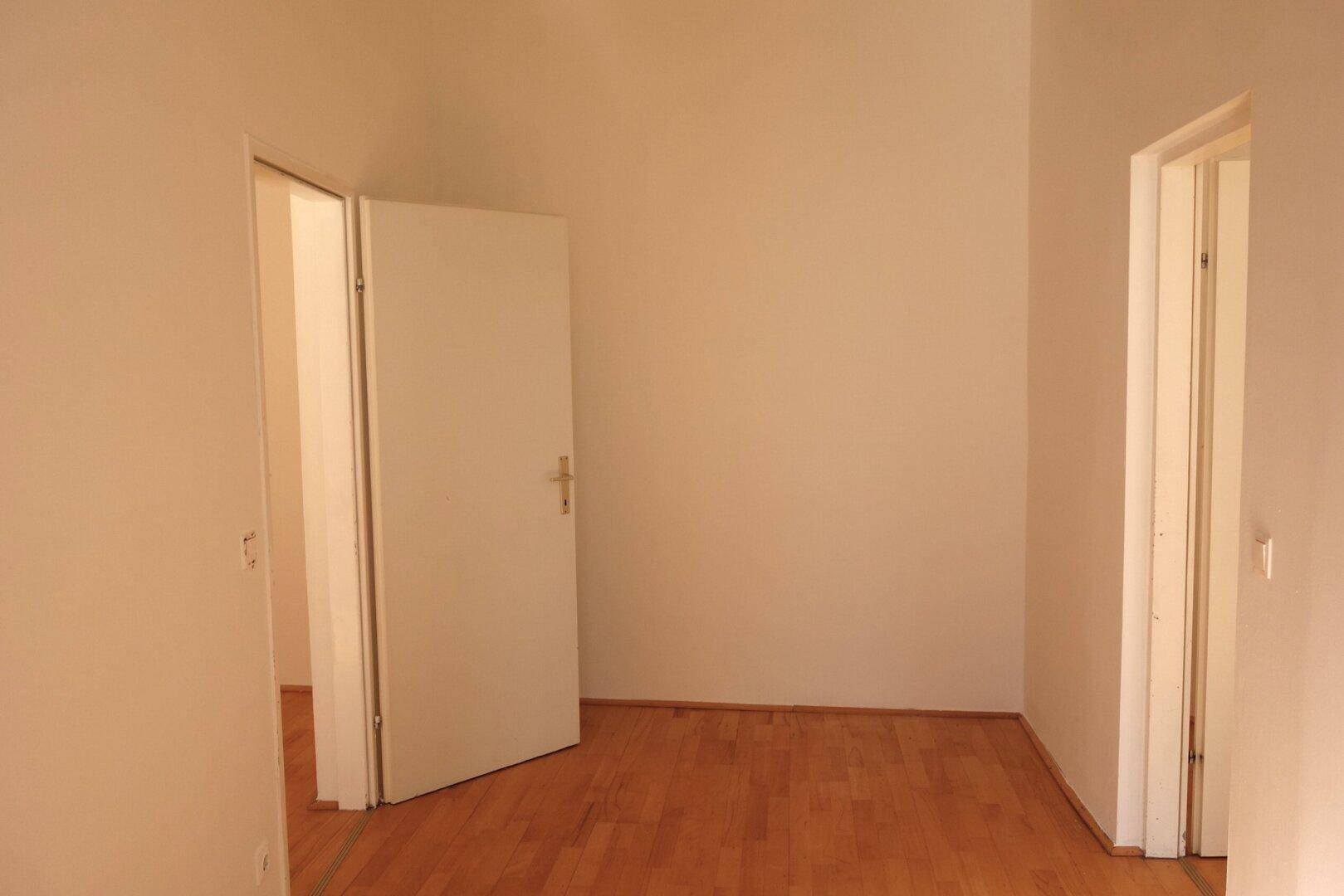 Heller Flur mit Holzboden und mehreren offenen Türen, die zu anderen Räumen führen.