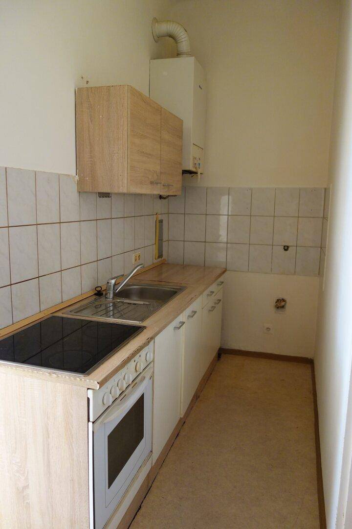Einfache Küchenzeile mit Spüle, Herd und Oberschränken, ideal für eine kleine Wohnung.
