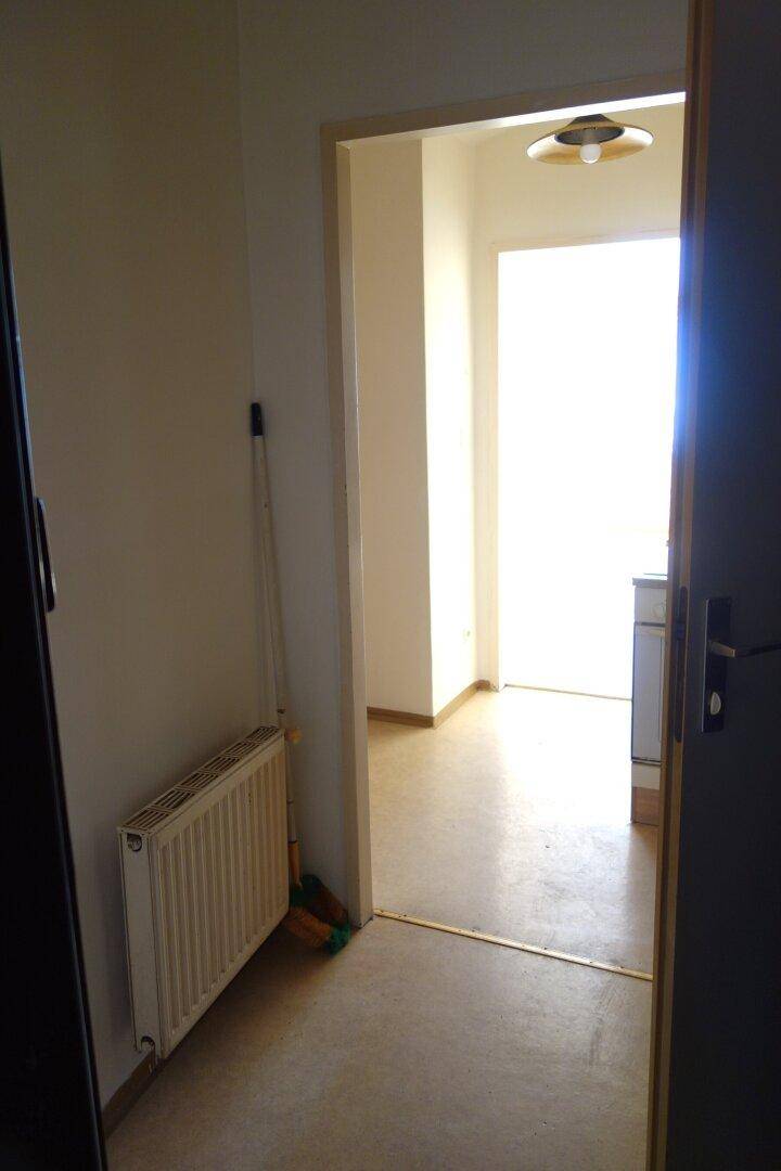 Flur mit Heizkörper und Blick in einen hellen Nebenraum, der viel Licht empfängt.