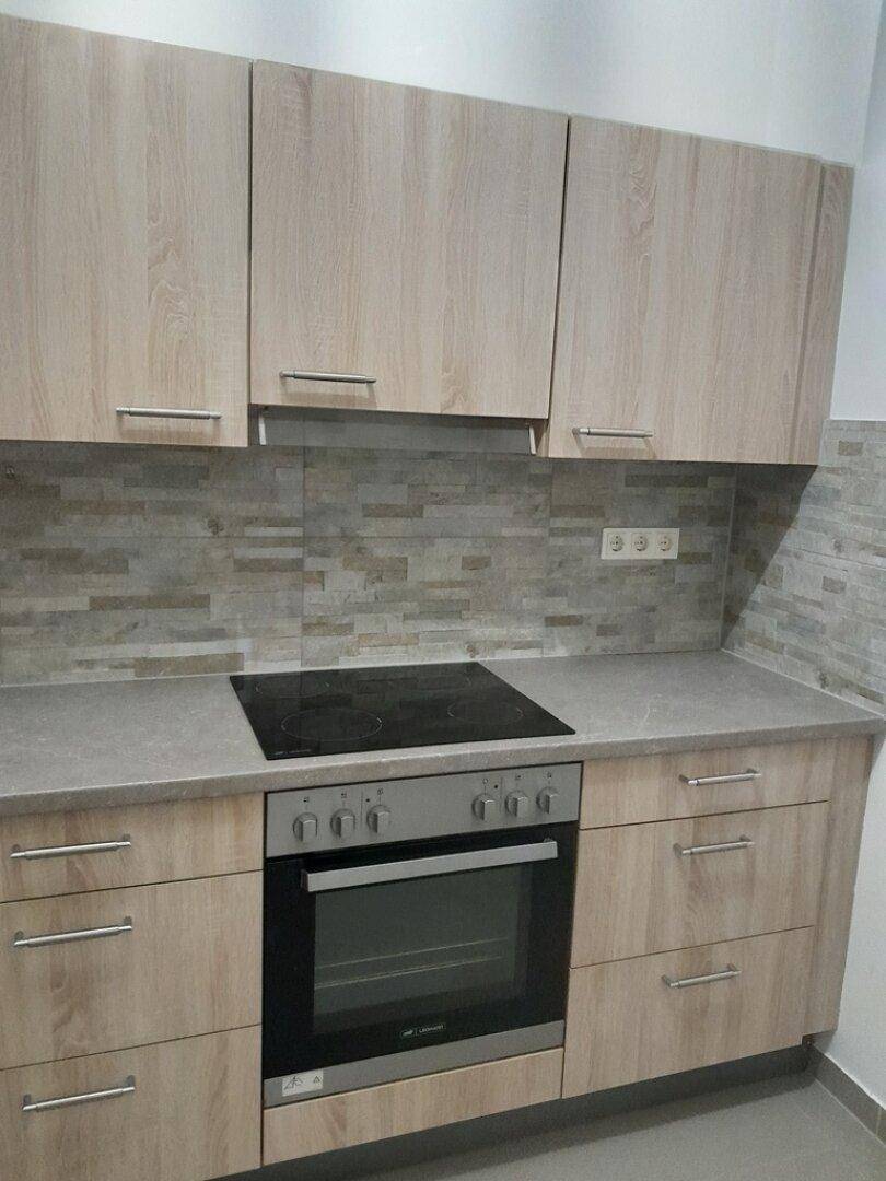 Funktionale Küche mit integriertem Backofen, Induktionskochfeld und hellen Holzschränken.
