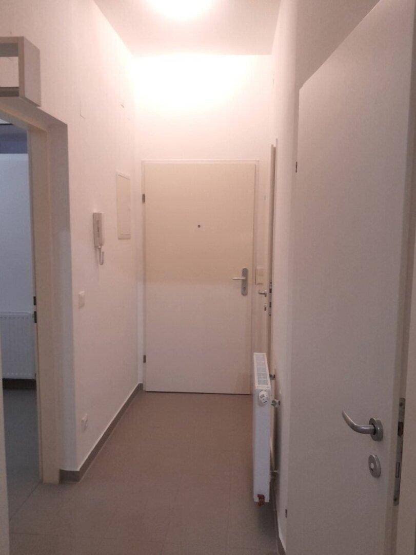 Heller Flur mit Fliesenboden und Eingangstür, der zu den Wohnräumen führt.