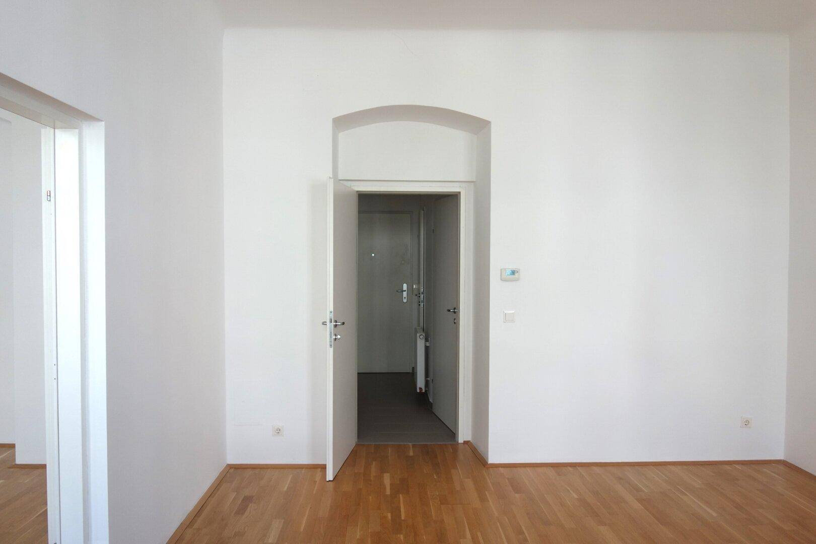 Geräumiges Zimmer mit Parkettboden und Zugang zum Flur, ideal für Wohnzwecke.