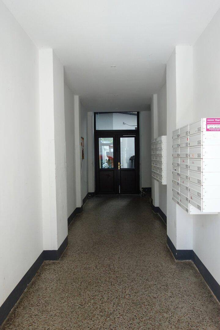 Langer, heller Hausflur mit Briefkästen an der Wand und einer Doppeltür am Ende des Ganges.