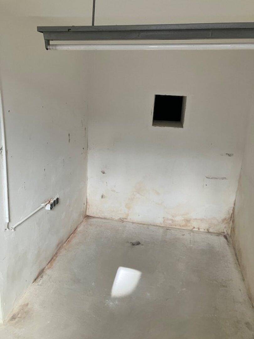 Kleiner, leerer Raum im Kellergeschoss mit Betonboden und einer Öffnung in der Wand.