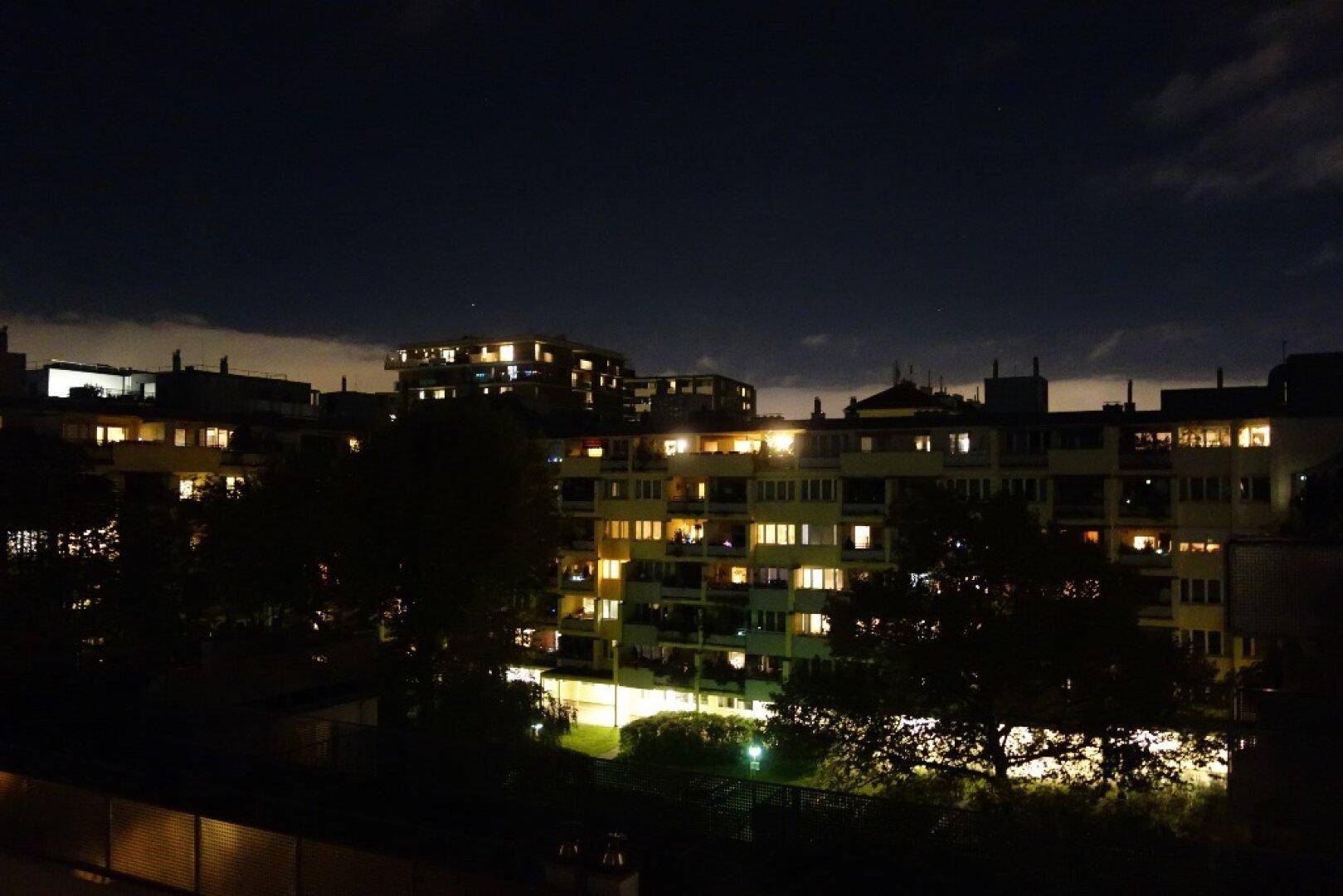 Nächtlicher Blick auf beleuchtete Wohngebäude in einer städtischen Umgebung.