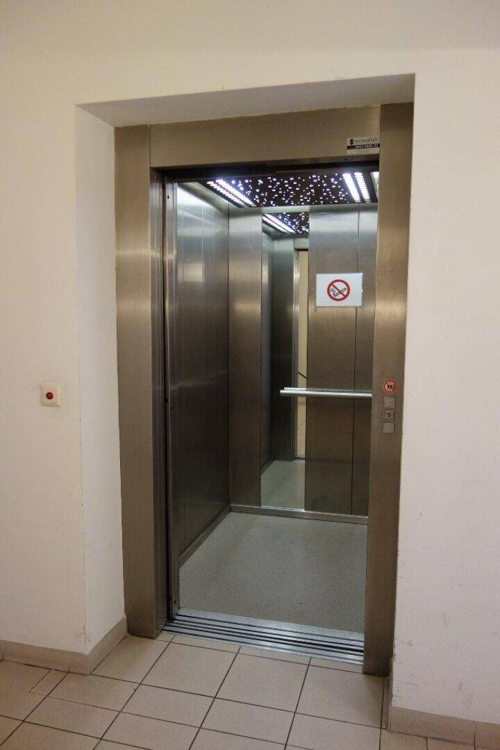 Moderner Aufzug mit Edelstahlinnenraum und dekorativer Deckenbeleuchtung im Gebäude.