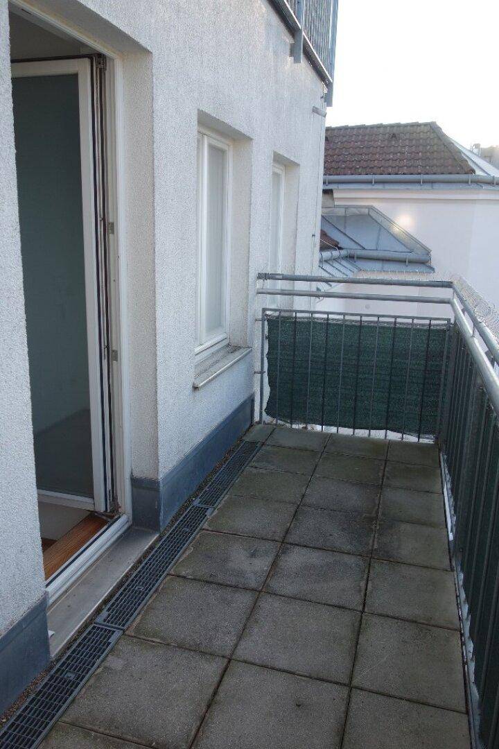 Balkon mit Fliesenboden und Metallgeländer, der einen Außenbereich zum Entspannen bietet.