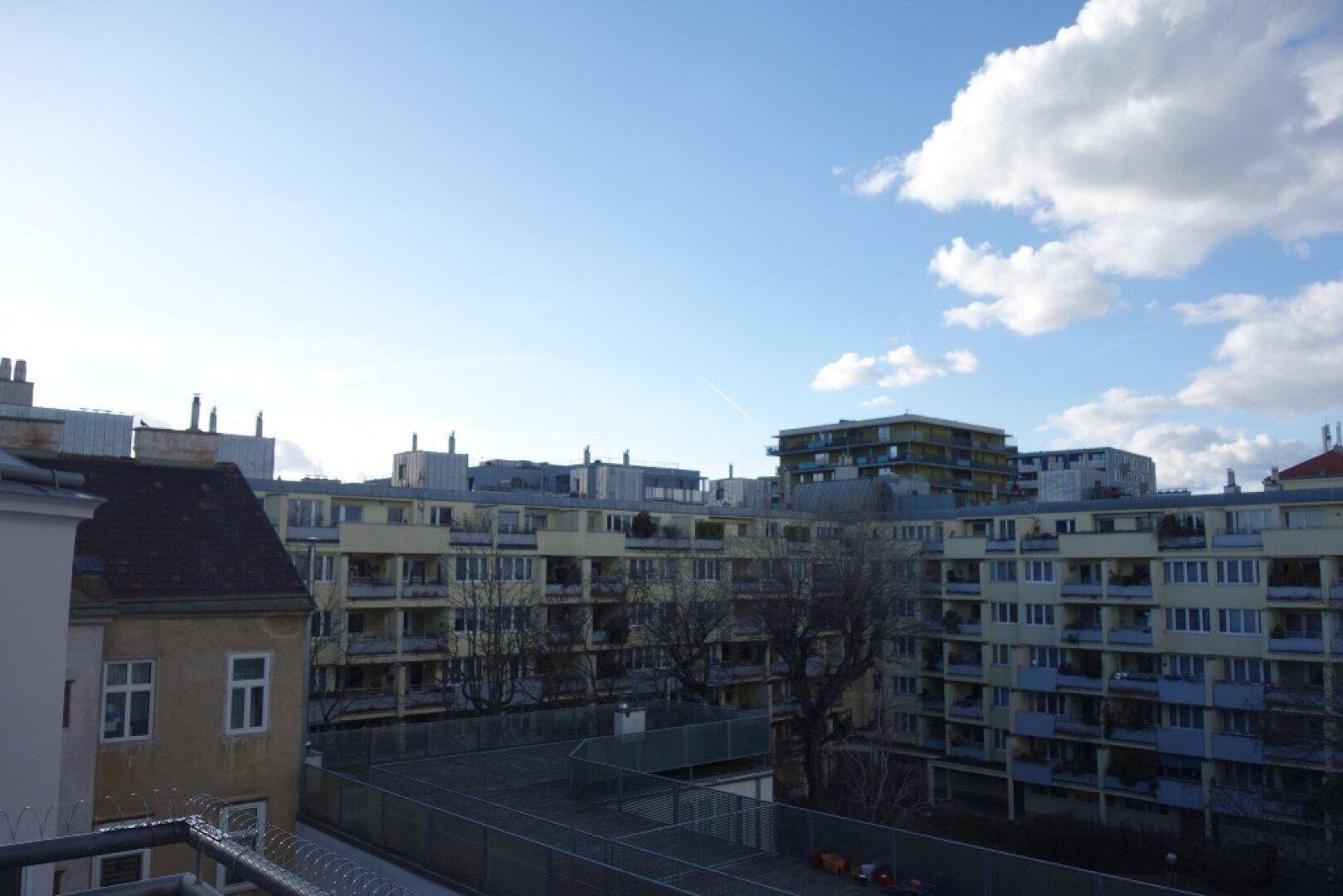 Blick auf mehrere Wohngebäude unter blauem Himmel mit leichter Bewölkung und Balkonen.