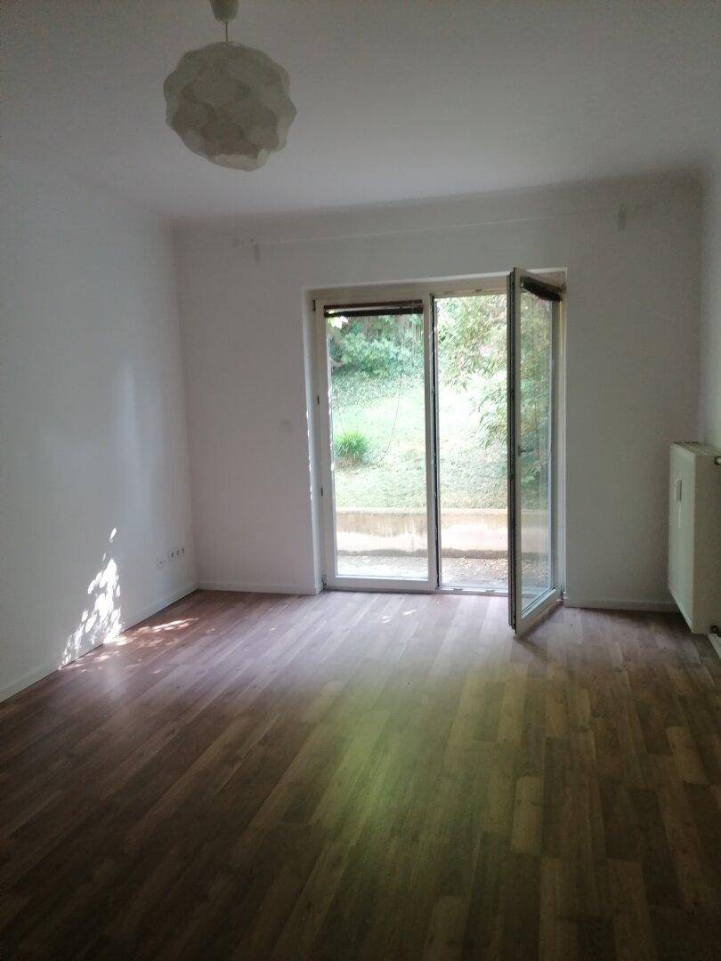 Heller Wohnraum mit Laminatboden und direktem Zugang zum Gartenbereich durch eine Glastür.