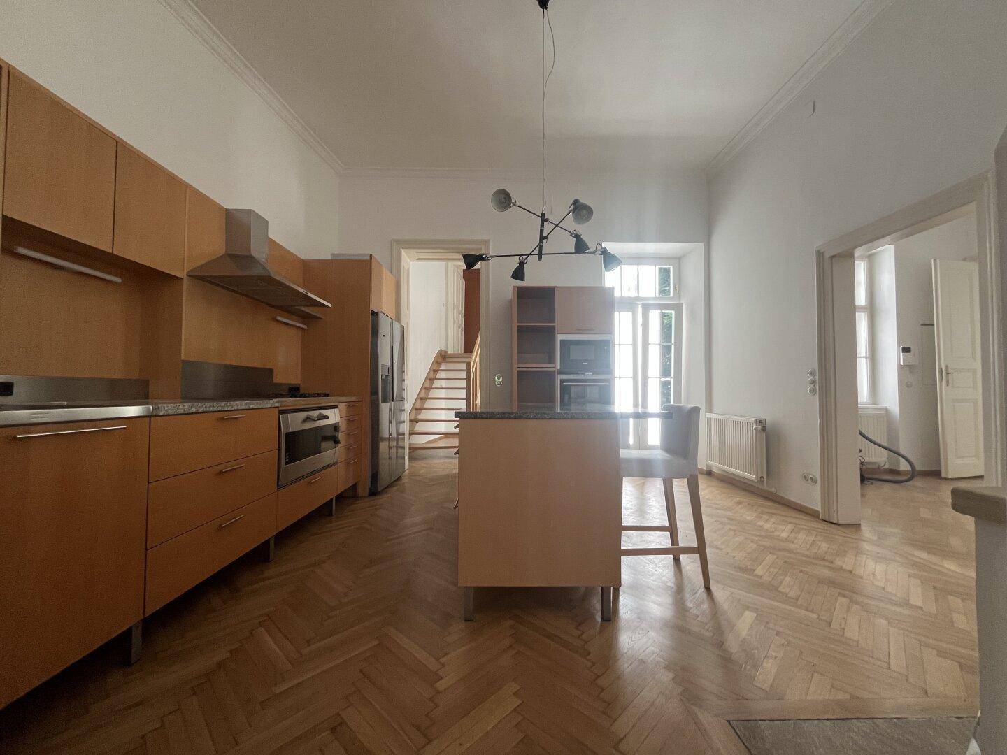 Geräumige Küche mit Holzschränken, Kücheninsel und modernen Geräten, offen zum Wohnbereich.