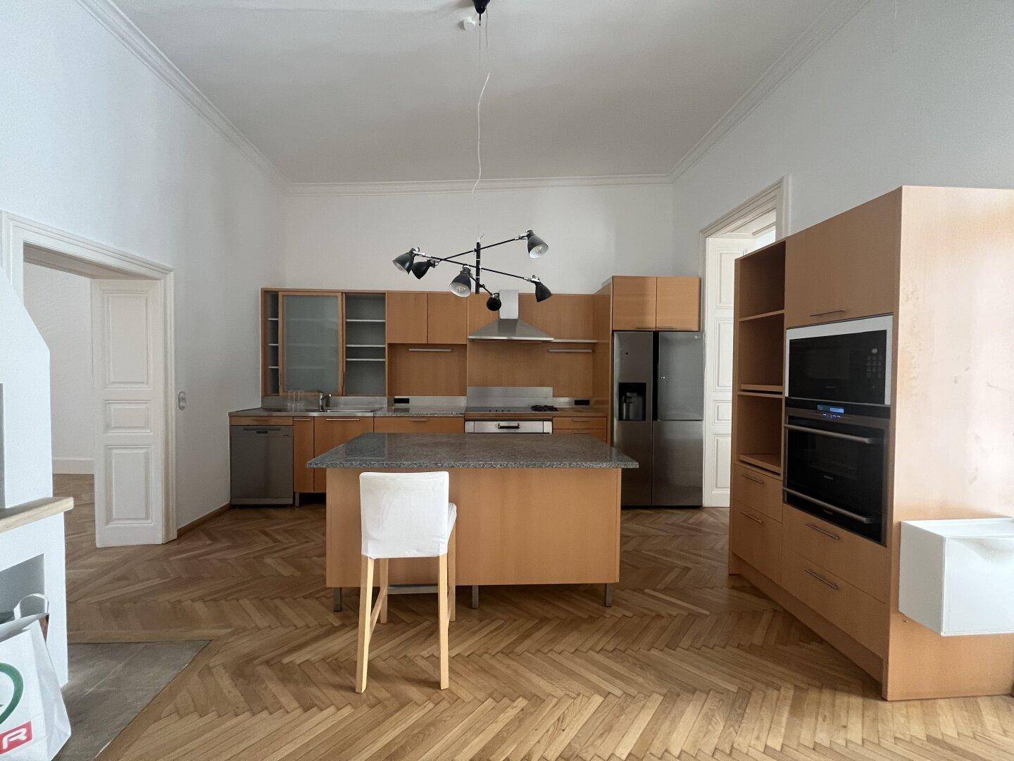 Moderne Holzküche mit Kücheninsel, integrierten Geräten und viel Stauraum.