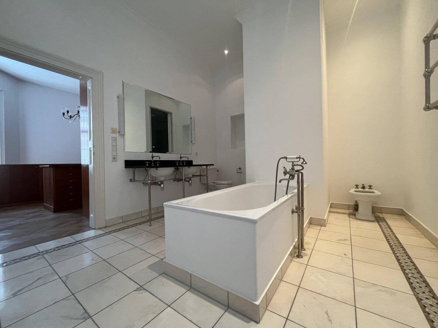Geräumiges Badezimmer mit Badewanne, Doppelwaschbecken, Bidet und Fliesenboden.