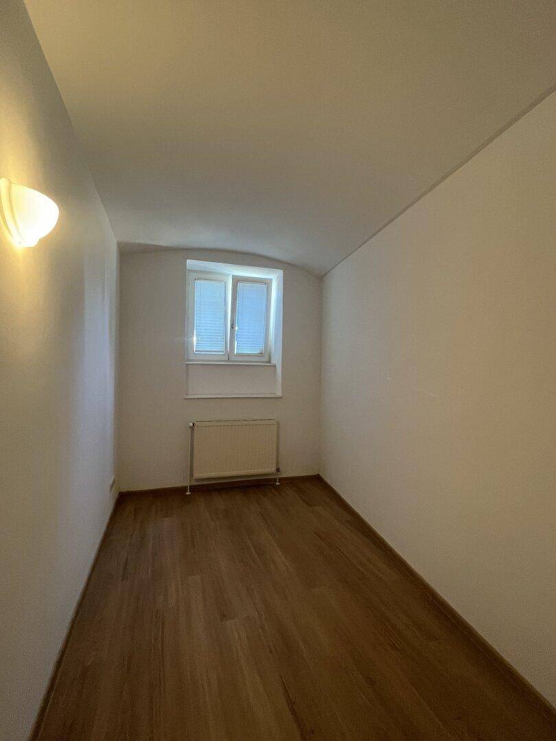 Kleines Schlafzimmer mit Holzboden und Fenster, ideal als Gästezimmer.