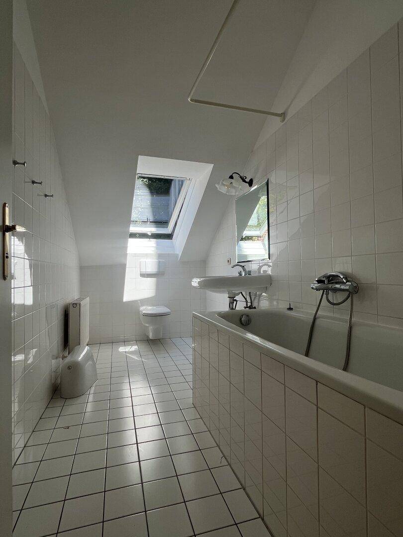 Badezimmer im Dachgeschoss mit Badewanne, WC, Waschbecken und Dachfenster.