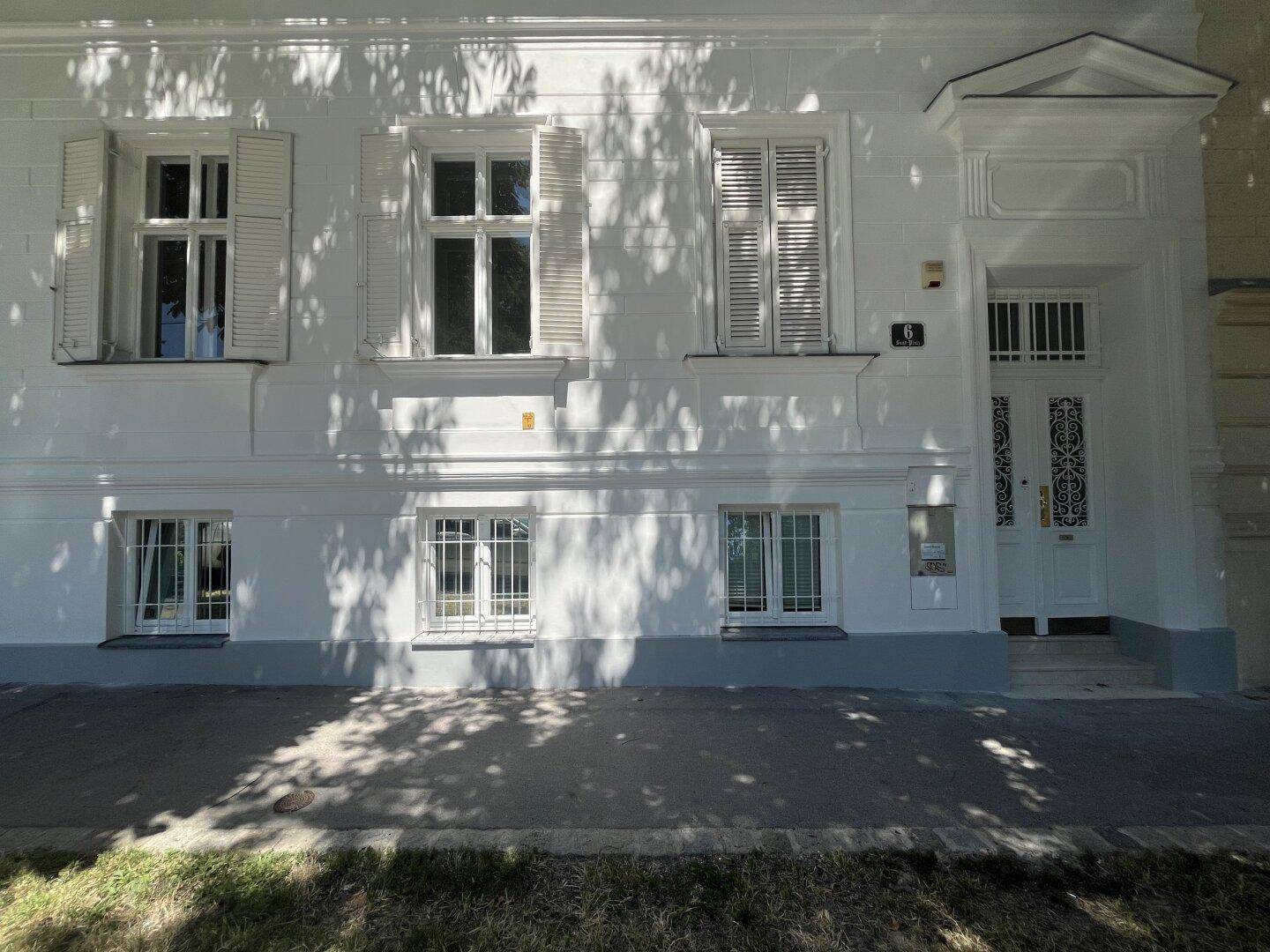 Klassische weiße Fassade eines Altbaus mit Fensterläden und elegantem Eingangsbereich.