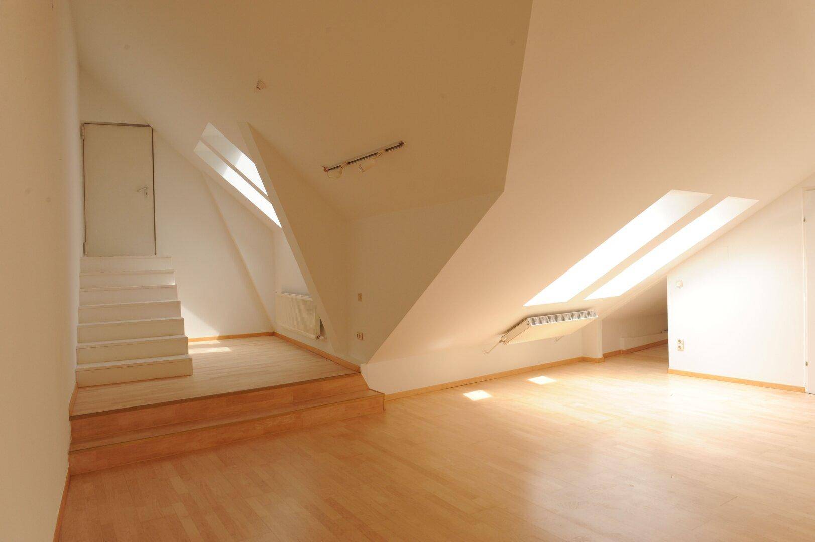 Heller Dachbodenraum mit Holzboden und Dachfenstern, bietet vielseitige Nutzungsmöglichkeiten.