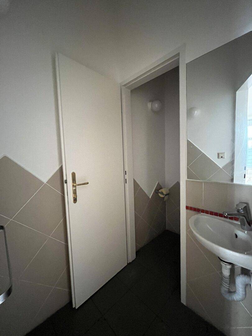 Kleines Badezimmer mit Waschbecken, Fliesen an den Wänden und dunklem Boden.