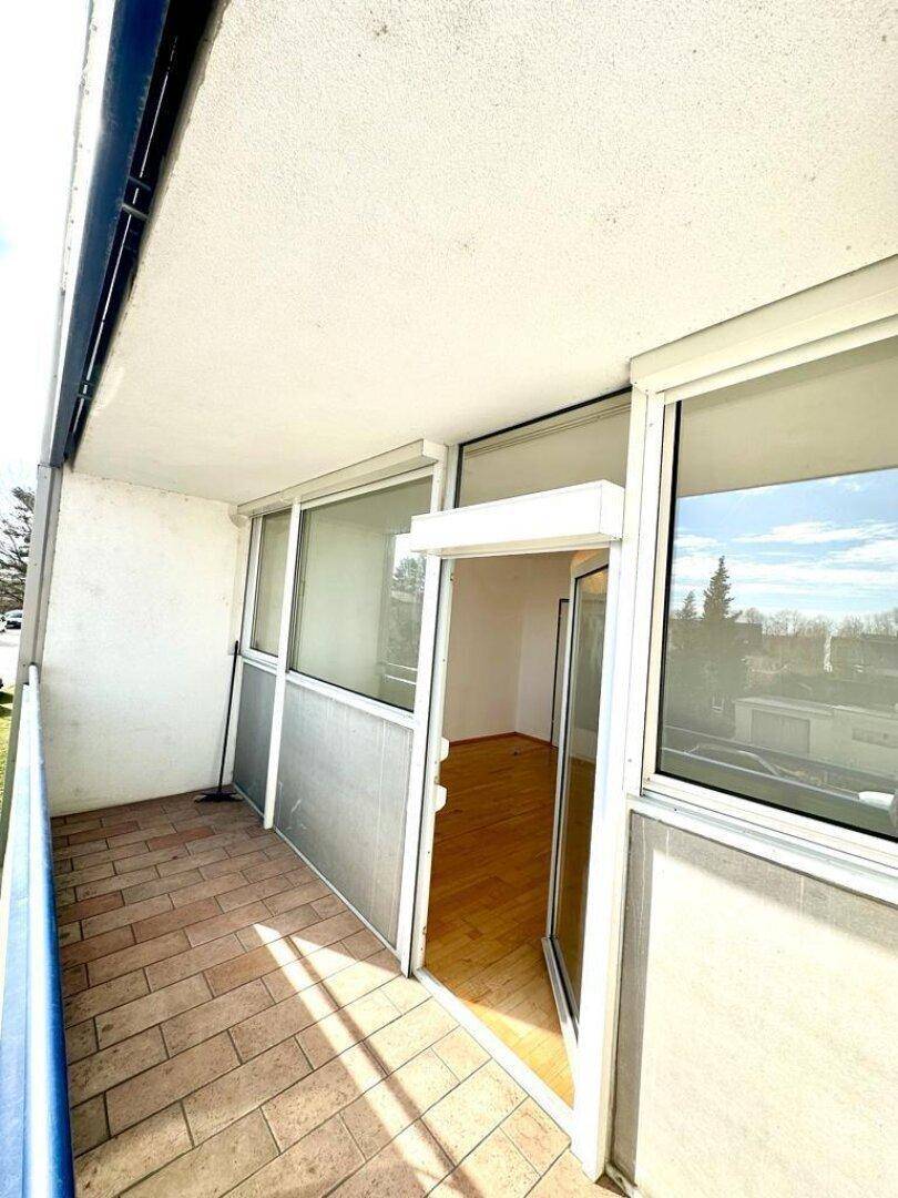 Geräumiger Balkon mit Fliesenboden und direktem Zugang zu einem hellen Innenraum der Wohnung.